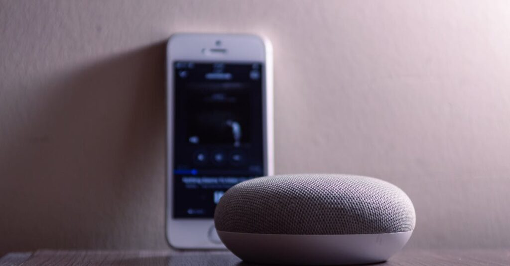 A modern smart speaker and smartphone on a wooden table, indoors.